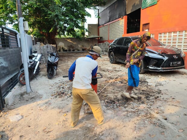Proses pembongkaran coran lama di area parkir